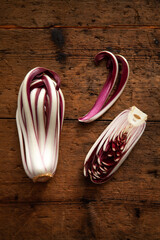 whole and cut red radicchio di Treviso on wooden table. View from above