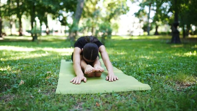 Athletic young woman doing yoga in the Park in the morning.