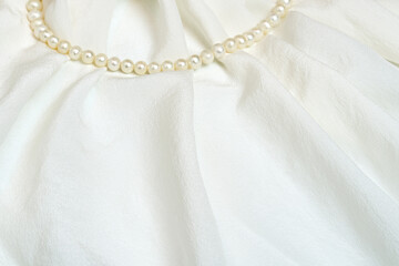 Beautiful white waved silk fabric with pearl beads. Romantic and elegant background.