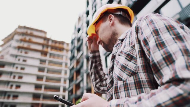 Inclusion of mobile applications in the development management process. Caucasian engineer builder in hard hat use on construction site mobile phone, engineer at work checking building project