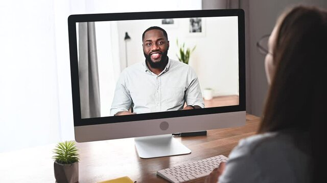 Online interview concept. An African American applicant is talking on the laptop screen, an hr employee listening. Video meeting, virtual conference of diverse work team