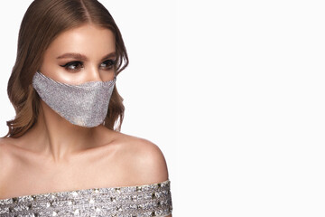 Portrait of a beautiful woman in a silver mask with rhinestones and classic makeup. Mask mode...