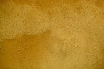 Weathered stained ochre wall background texture with rough plaster finish in close up in a full...