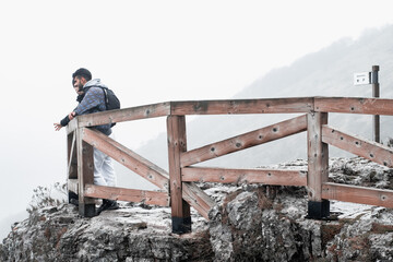 the hikers pose at the edge of a foggy mountain.