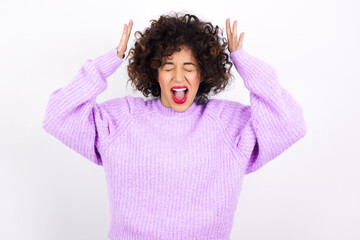 young beautiful caucasian woman wearing pink knitted sweater against white wall goes crazy as head...