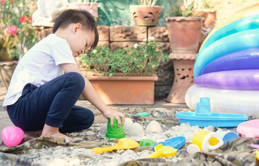 Cute Asian toddler boy playing with sand alone at home, Kid playing with sand toys in urban home...
