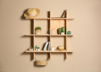 Wooden shelves with different decorative elements on beige wall