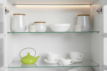 Fototapeta na wymiar Open kitchen cabinet with different clean dishware