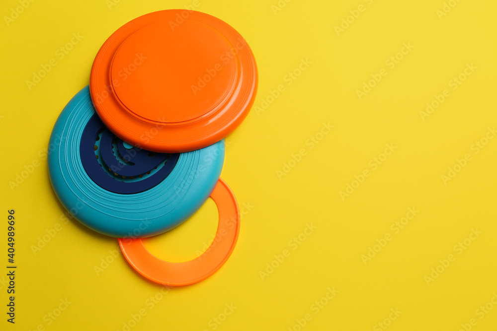 Poster Plastic frisbee disks and ring on yellow background, flat lay. Space for text