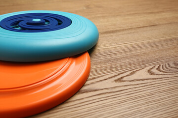 Plastic frisbee disks on wooden background, closeup. Space for text