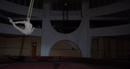 Blonde circus acrobat is hanging on silks with her neck, athletic people, 4k