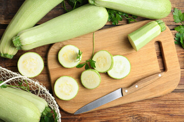 Ripe green zucchinis and parsley on wooden table, flat lay