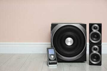 Modern powerful audio speaker system on floor near pink wall. Space for text