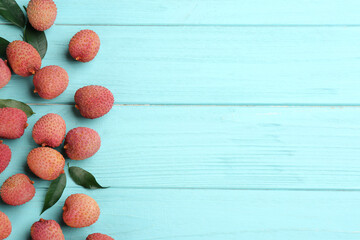 Fresh ripe lychee fruits on light blue wooden table, flat lay. Space for text