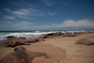 Fototapeta na wymiar Beautiful sandy ocean beach with large rocks on the shore and in the water