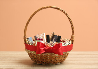 Wicker gift basket with cosmetic products on wooden table