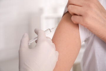 Doctor vaccinating woman against Covid-19 in clinic, closeup