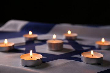 Fototapeta na wymiar Burning candles on flag of Israel. Holocaust memory day