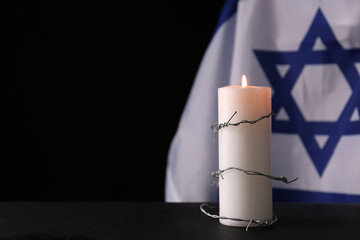 Barbed wire and burning candle on black background, space for text. Holocaust memory day