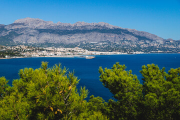 Fototapeta na wymiar Coastal view to Atea over mediteranean sea and blurred pines in natural park 'Serra Gelada' in Albir, Spain