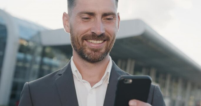 Close Up Portrait of Young Satisfied Businessman is texting Messages on his Smartphone. Handsome Man is wearing grey Suir, having nice Hairstyle. Successful People. Business. Social Neatwork.
