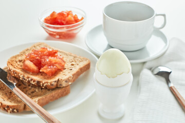 Boiled egg, toasts with apple jam and cup of coffee on white background, Selective focus on boiled egg