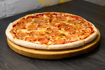 Pepperoni pizza on round tray on wooden table