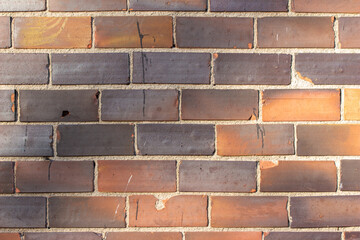 Obraz premium Full frame texture background of a vintage weathered tile brick wall with worn bricks having a scorched like appearance in colors of white, red, and brown