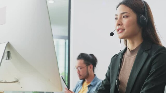 Asian beautiful young call center agent talking to customer by headset