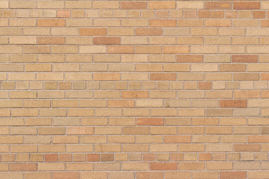 Full frame texture background of a vintage weathered brick wall in common bond pattern, with bricks in varying shades of orange and beige.