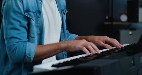 Portrait of Young stylish Hipster Musicant is playing Electronic Piano and singing in a professional Microphone. Handsome Musicant is singing with sensuous Emotions. Music. Hobby. Talent.
