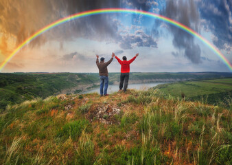 Fototapeta na wymiar Woman and man Looking At Rainbow. rainbow over river canyon 