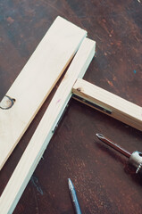 Woodworking with a drill to screw angle bracket in a wooden block with wood shavings and smoke in a woodworking workshop close-up power tool