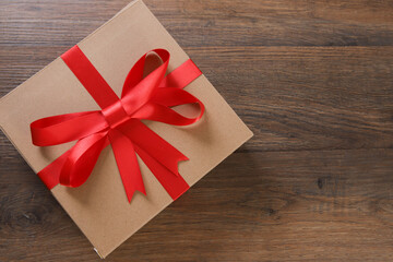 Brown and red gift boxes and red ribbon on wooden background with space