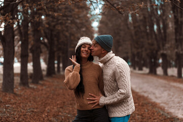 Close up of a beautiful young happy couple in love embracing while spending time in the autumn park
