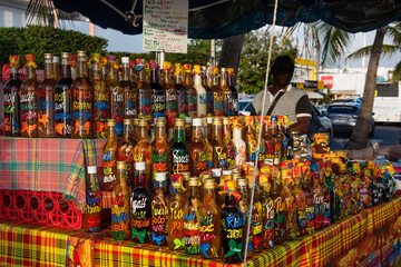 Typical tourist market in Guadeloupe selling traditional beverages, spices and other itens. - 405016824