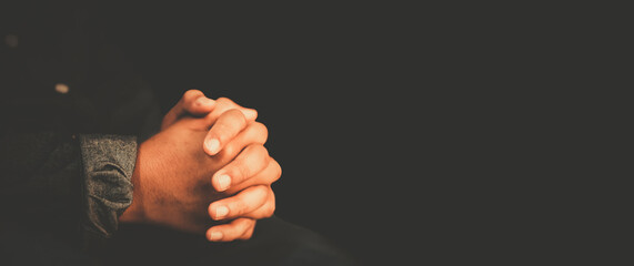 man praying worship at home on black background.Teenager hand praying,Hands folded in prayer.Good...