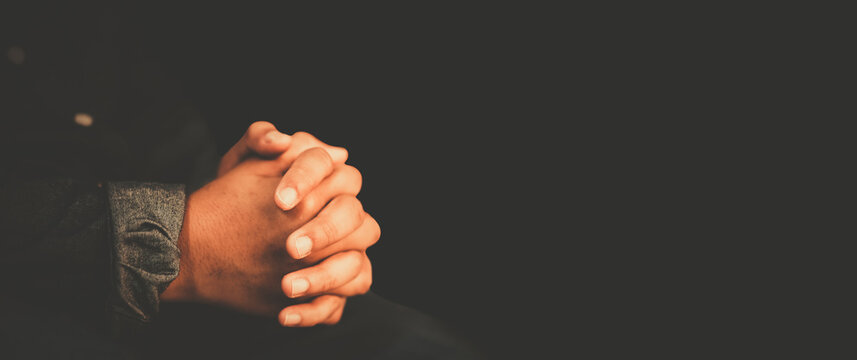 man praying worship at home on black background.Teenager hand praying,Hands folded in prayer.Good friday, Easter, forgiveness.Concept for faith, people, fasting and religion.stay home, lockdown.
