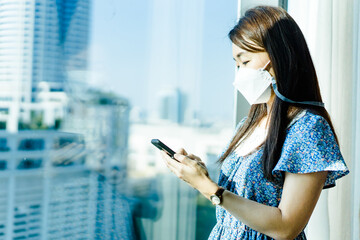 Asian woman check her phone for news update about covid19.Patient woman with medical mask check infection people around her home.Technology, Healthcare medical, Smartphone, Application for health.