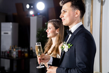 newlyweds with champagne in hands listen to toasts, congratulations from guests