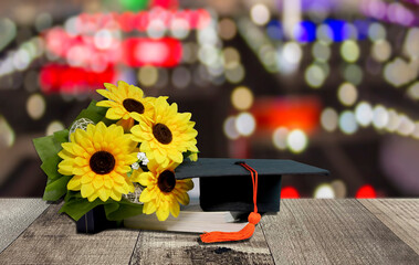Graduation cap and textbook on wooden table with light bokeh background. Concept of global business study, abroad educational, Back to School.
