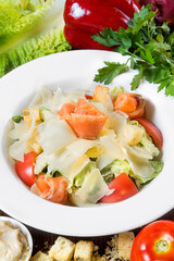 Seafood Caesar salad with shrimp, arugula, and parmesan cheese on a round white plate.