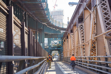 Fototapeta na wymiar Workers and joggers using pedestrian walkway on gigantic bridge from New York City to Long Island City
