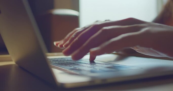Close up A woman's hand using a computer keyboard in the morning sunshine. Business women work from home .