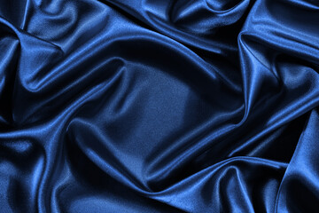 Blue silk satin background. Shiny fabric with wavy folds. Beautiful fabric background with empty...