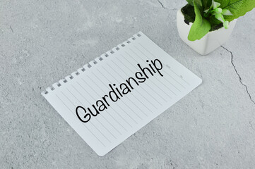 Top angle view of plant and white paper written with text GUARDIANSHIP. Business concept. 