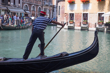 Fototapeta na wymiar Gondoliero drives a gondola on a canal in Venice