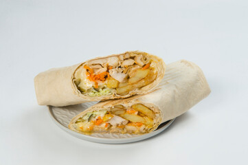 Close up of Chicken meat Shawarma roll with cabbage, cucumber, French fries potato, cheese wrapped in thin lavash bread served on plate, isolated on background. Greek Gyros roll. Turkish grilled doner