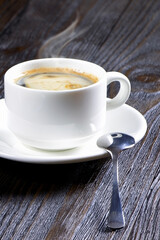 A white cup of coffee on a wooden background. Espresso. Morning coffee. Coffee cup. Vertical orientation