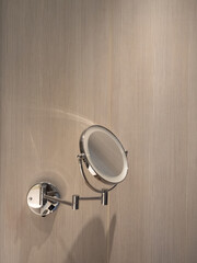 Round washroom mirror on wooden wall with light effect in bathroom.